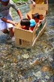 段ボールいかだで川遊びする人たち